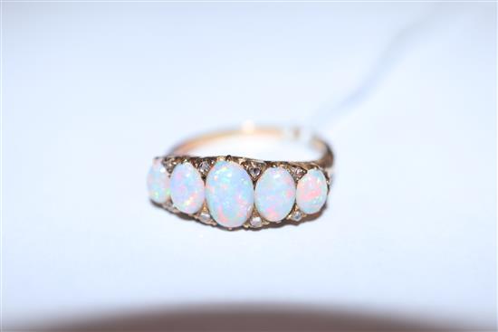 An early 20th century 18ct. gold, graduated five stone white opal and diamond chip half hoop ring, size O.